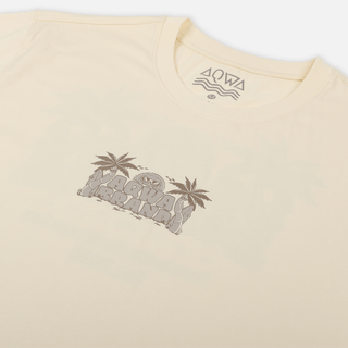 Close-up of AQWA logo on the chest of the cream surf tee with tropical sun and palm details – clean and coastal.