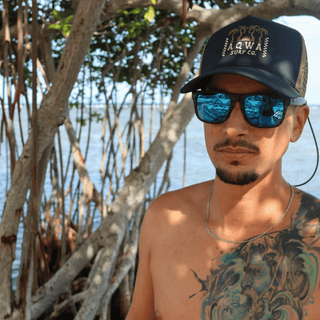 AQWA navy palm tree hat worn by model near the mangroves, reflecting adventure-ready spirit.