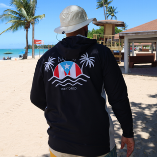 AQWA hoodie with Puerto Rico flag and palm tree print, worn on tropical beach — symbol of island pride and coastal identity.