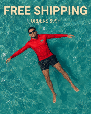 Close-up aerial shot of man relaxing in turquoise ocean water wearing a red AQWA hooded rash guard and black swim shorts — lightweight UV protection apparel inspired by Puerto Rico beach and boating lifestyle.