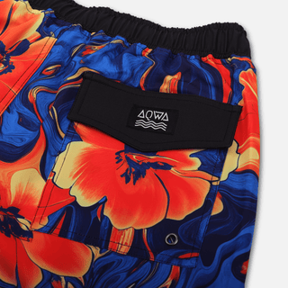 Detailed close-up of AQWA back pocket on vivid red-orange floral swim trunks – highlighting stitching, logo, and drainage.