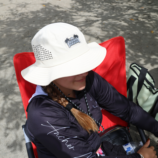 AQWA white boonie hat with palm tree logo, worn by woman relaxing under shade — ideal for fishing, boating, and beach chill days.