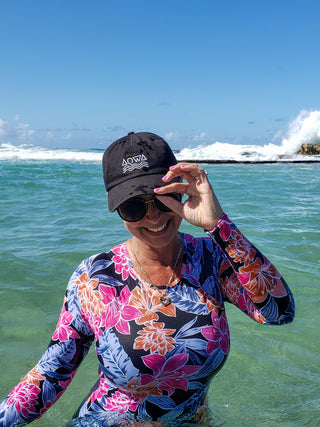 Beautiful women smiling and joining the beach, wearing a flower swimsuit and an AQWA dad hat